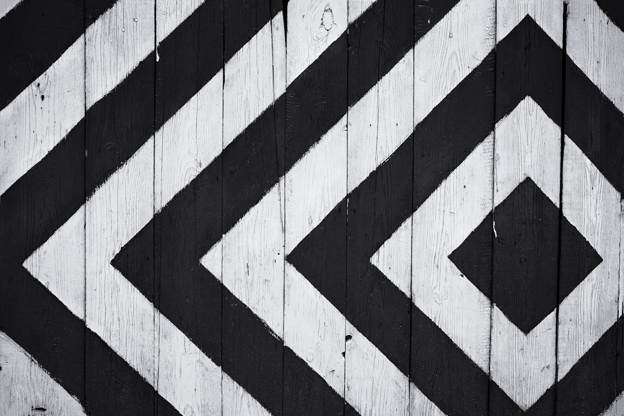 our-services-02 Black and white geometric pattern on wooden planks, ideal for modern design backgrounds.